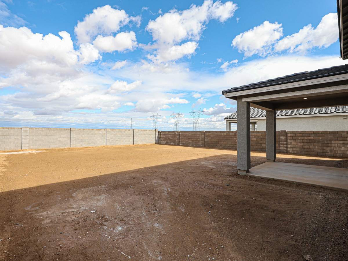 A sandy area with a fence and a building in the background.