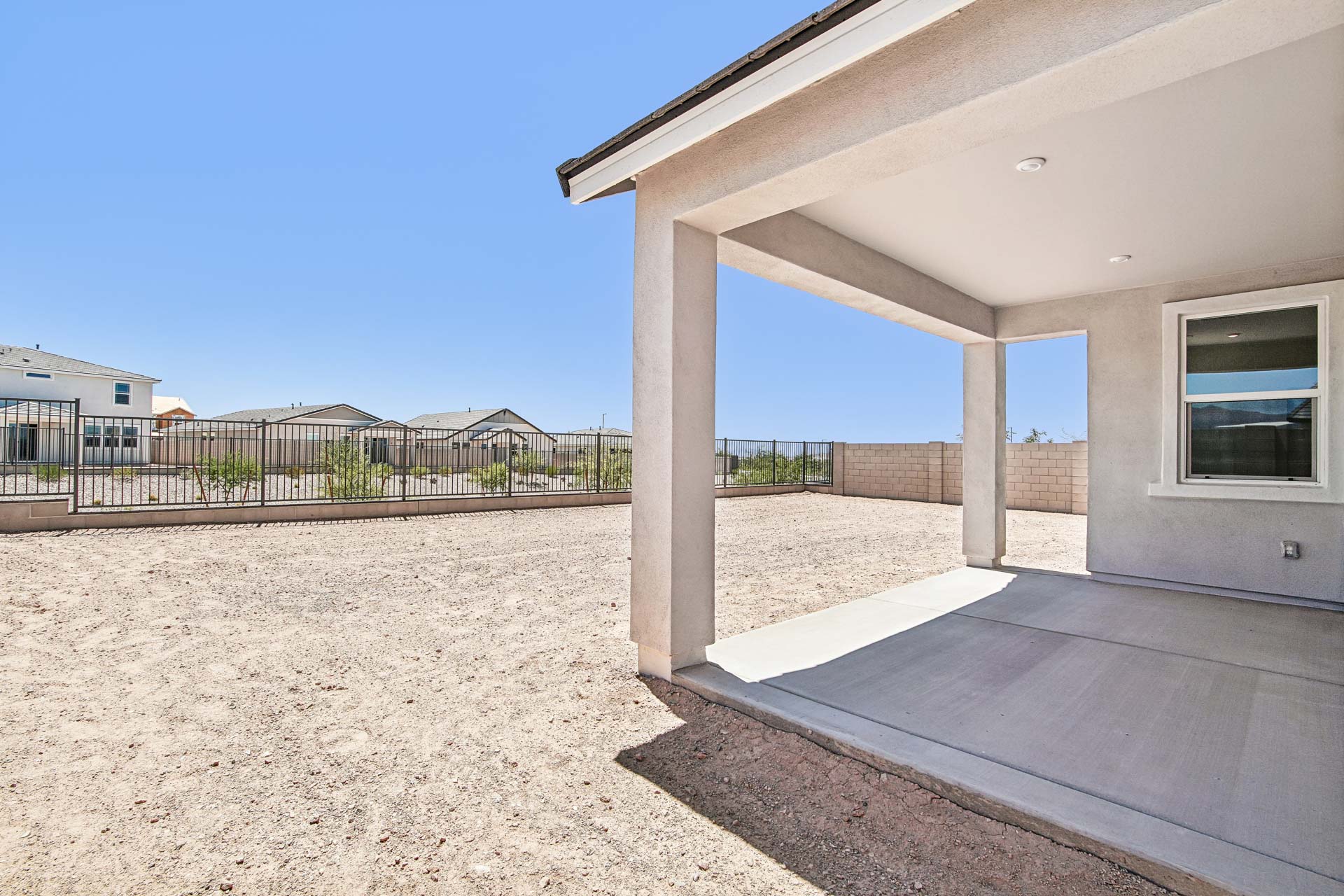 A building with a fence and a sandy area.