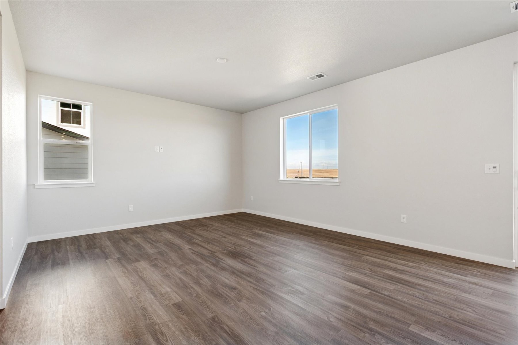 A room with a wood floor and windows.