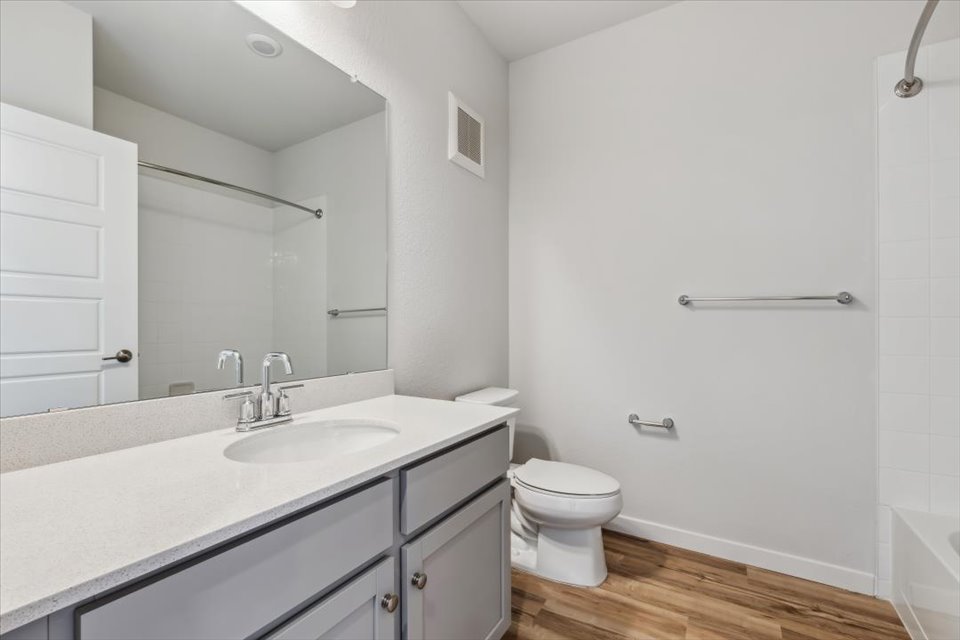 A bathroom with a sink toilet and mirror.