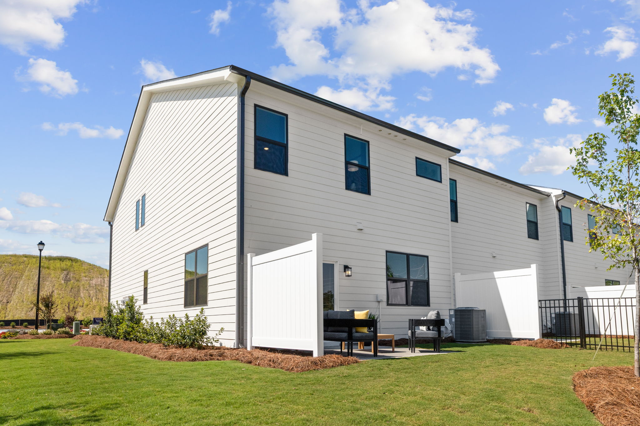 A white building with a lawn in front of it with Rockingham Meeting House in the background.