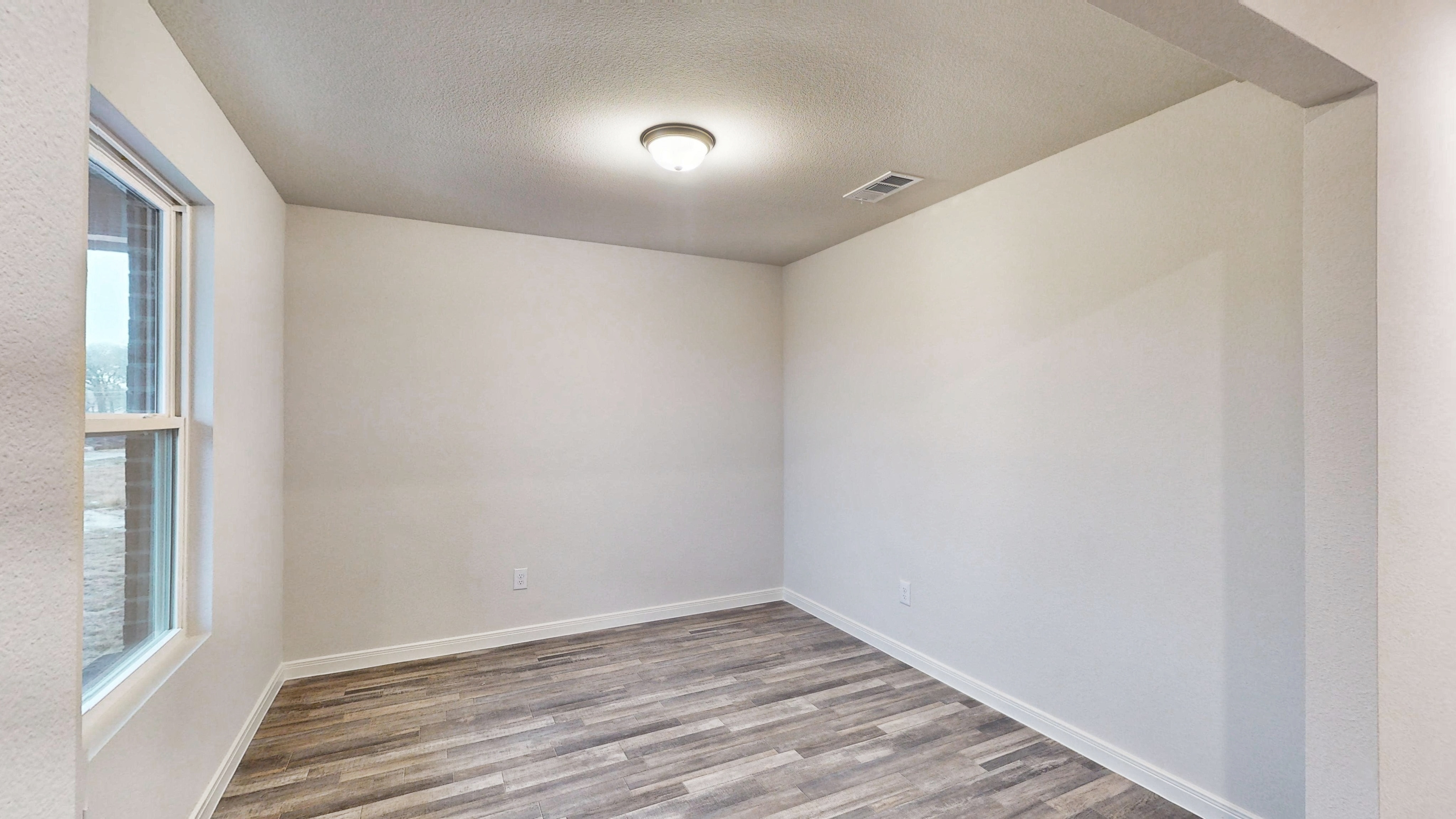 A room with a wood floor and windows.