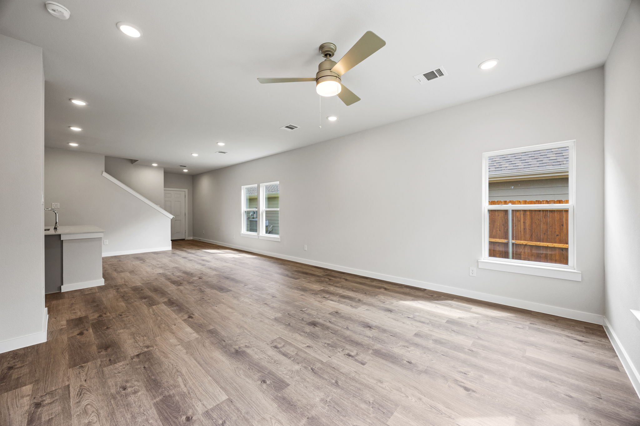 A large empty room with a wood floor and a ceiling fan.