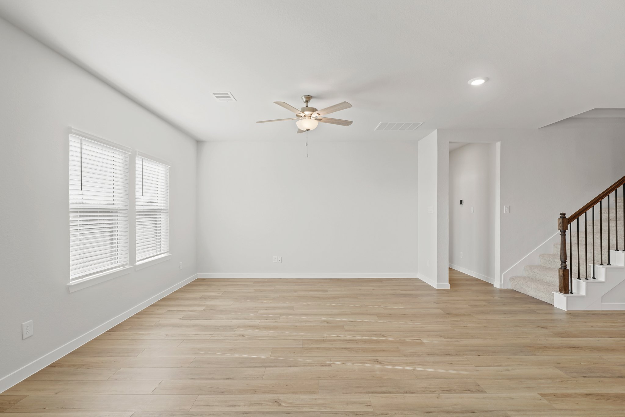 A room with a wood floor and a ceiling fan.