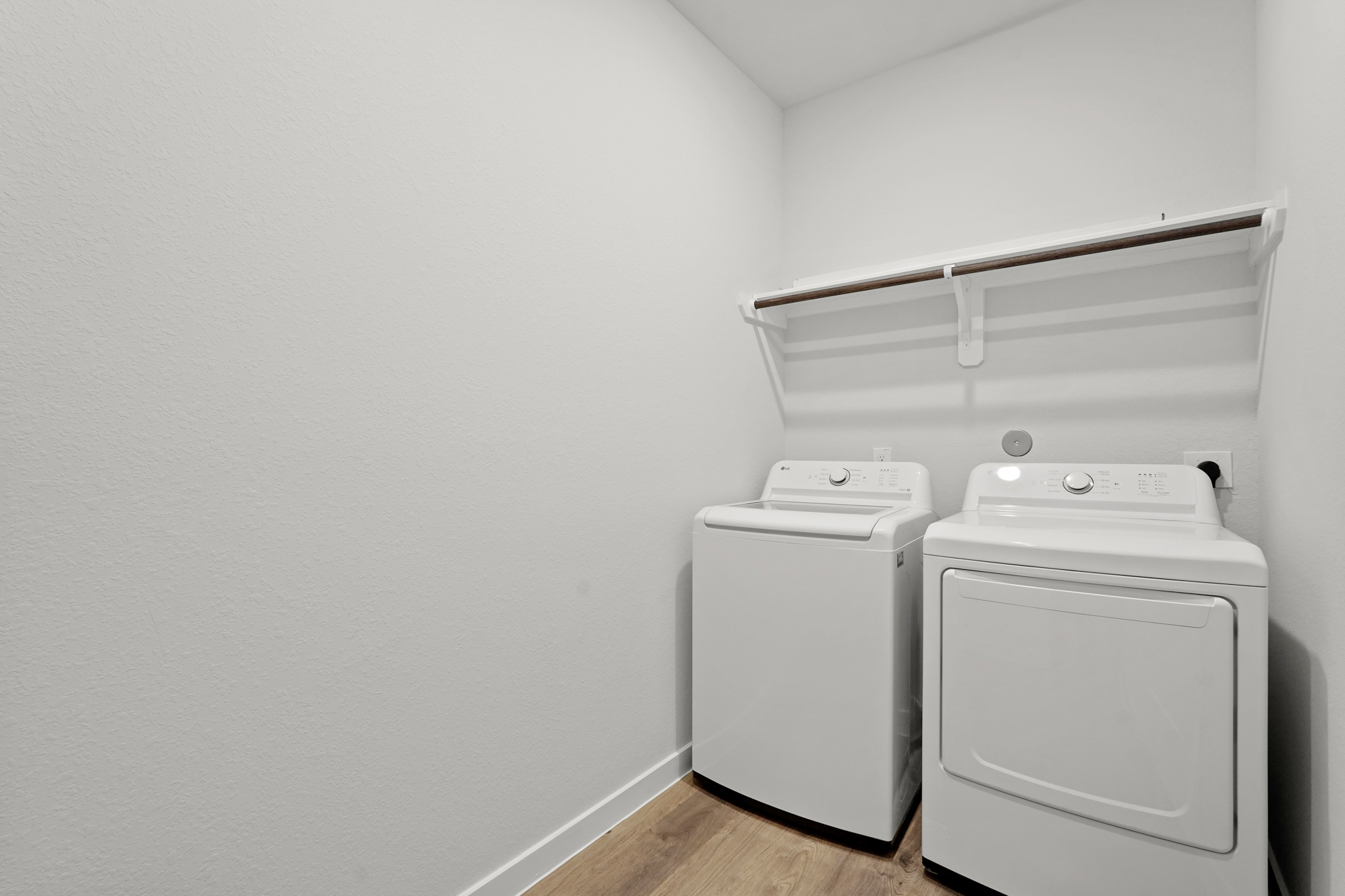 A white wall with a white machine and a white shelf.
