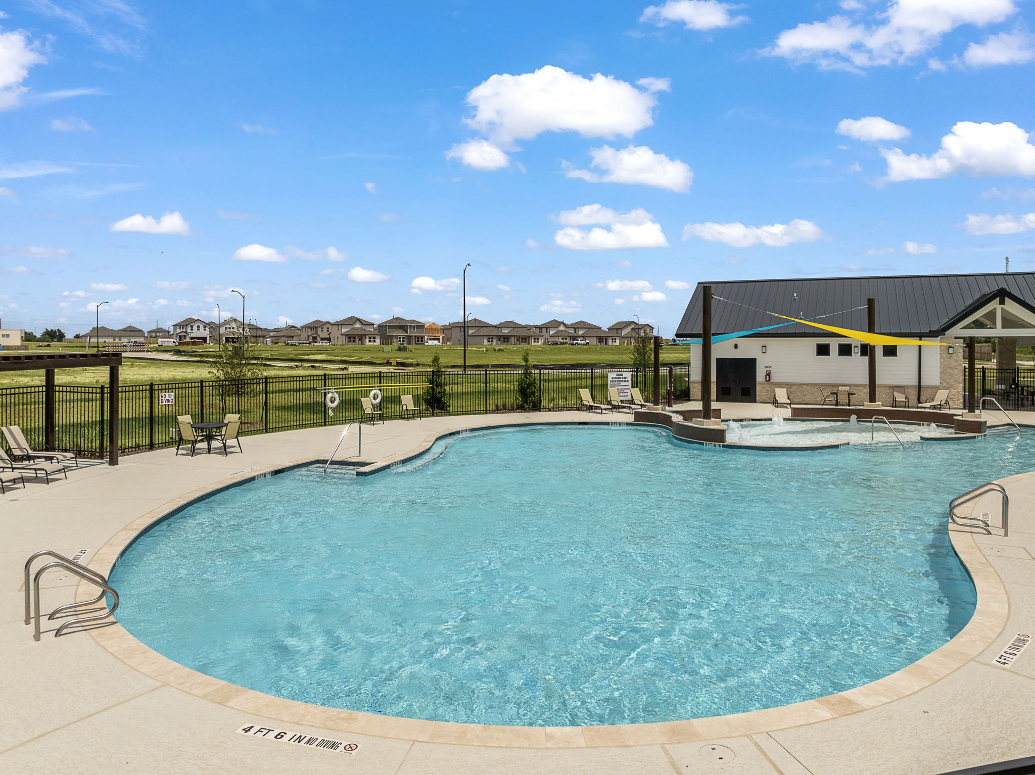 A swimming pool with a fence and buildings in the background.