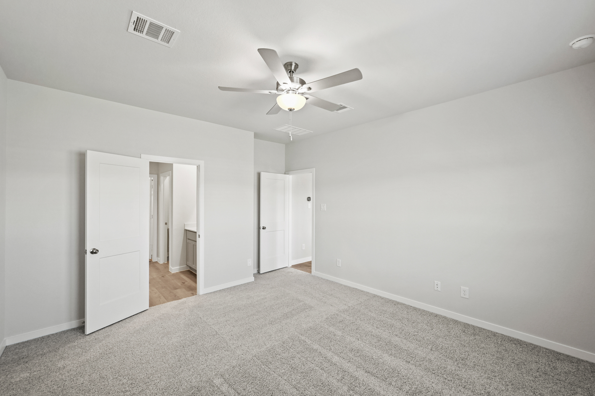 A room with a ceiling fan and white walls.