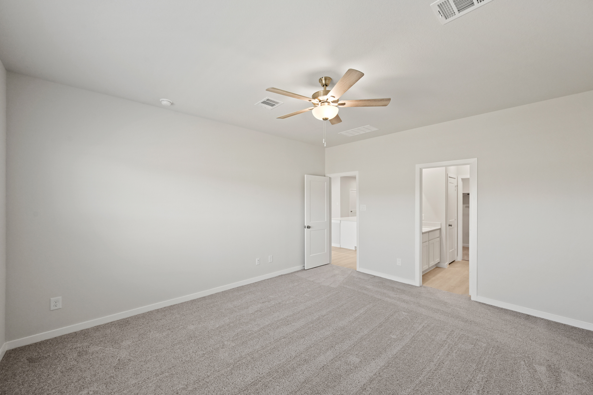 A room with a ceiling fan and a carpet.