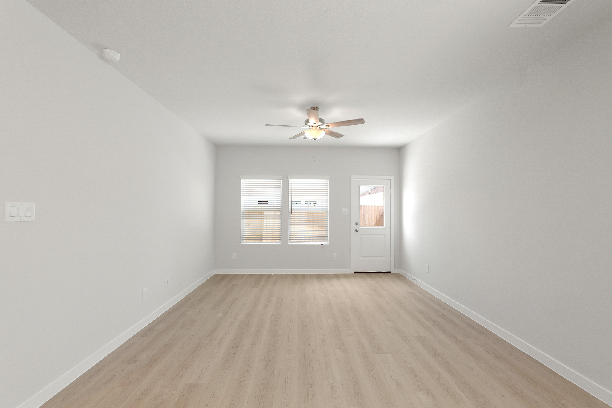 A room with a ceiling fan and a wood floor.