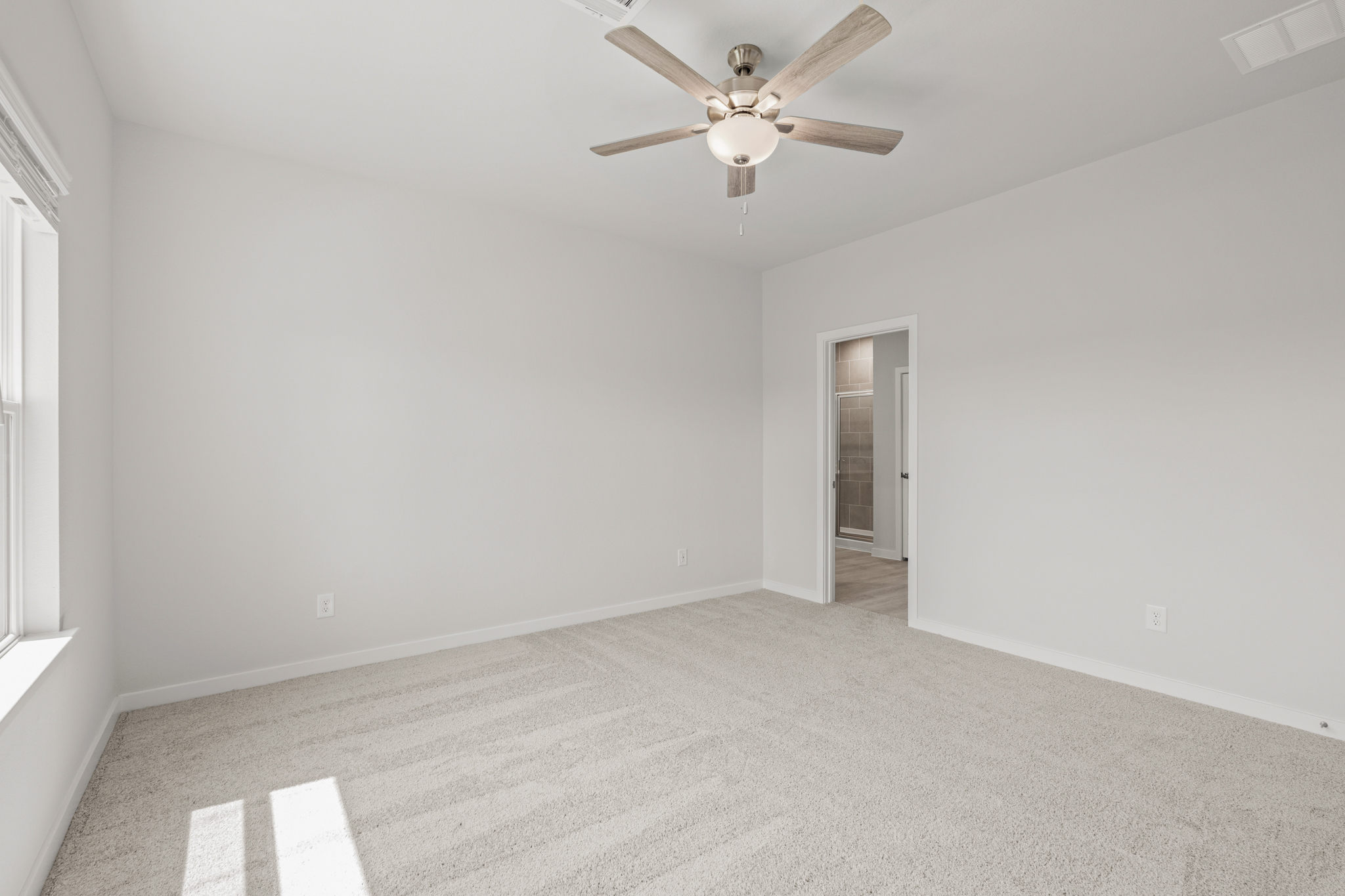 A room with a ceiling fan and a door.