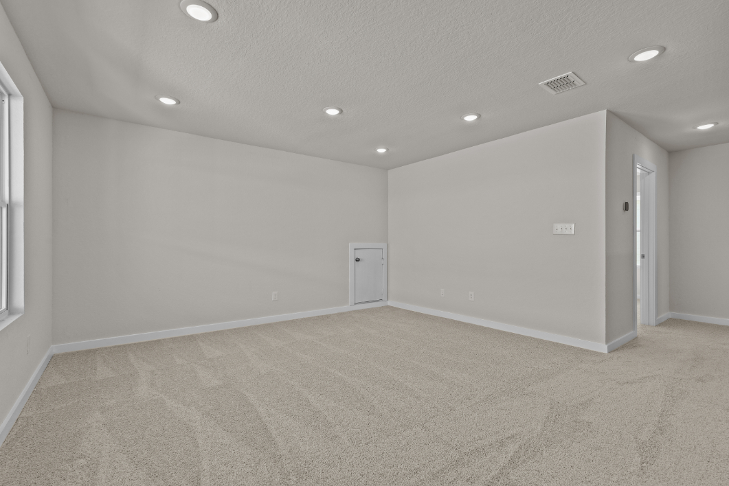 A room with a carpet and a white wall.