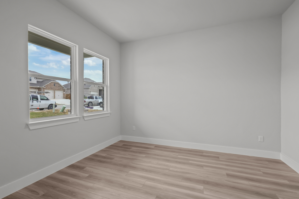 A room with a wood floor and a window with a view of the street.