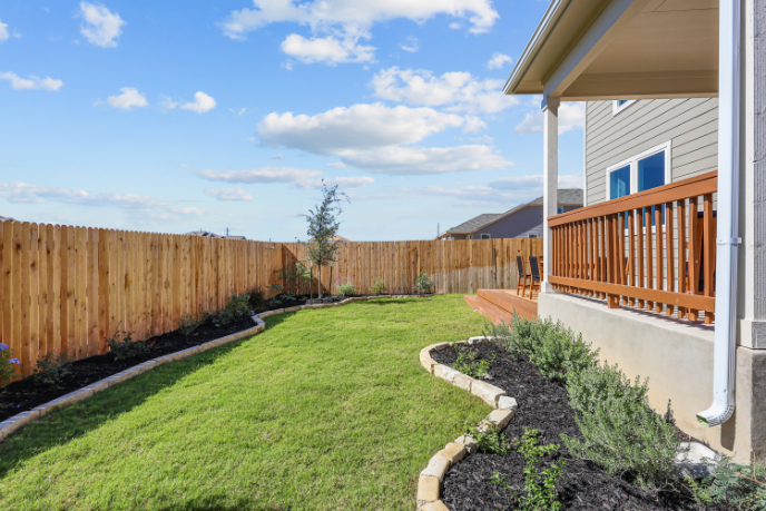 A backyard with a fence and a house.