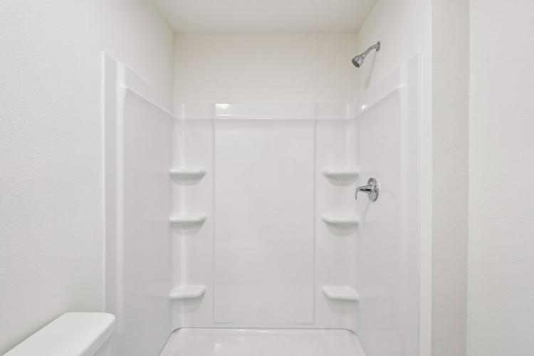 A bathroom with a shower unit and toilet.